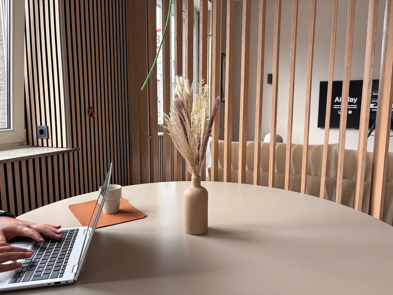Beratungstisch im Showroom mit Laptop und Trockenblumen vor Eichenlamellen